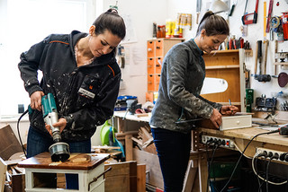 Zwei Frauen werkeln in ihrer Werkstatt und werten alte Möbel auf