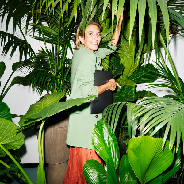 Person walks with laptop in her hand surrounded by plants