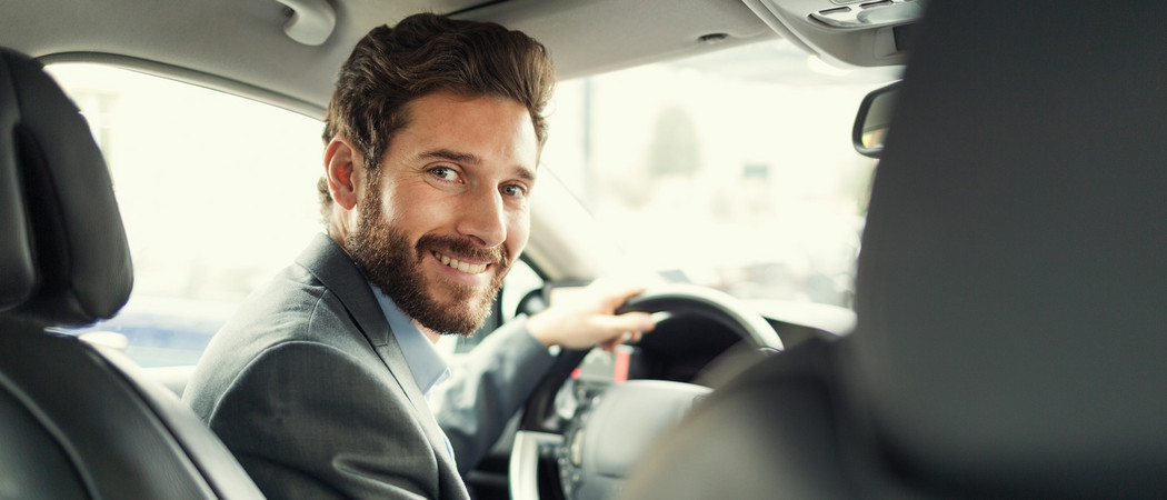Junger Mann lächelt am Steuer eines Gebrauchtwagen - Tipps beim privaten Autoverkauf.