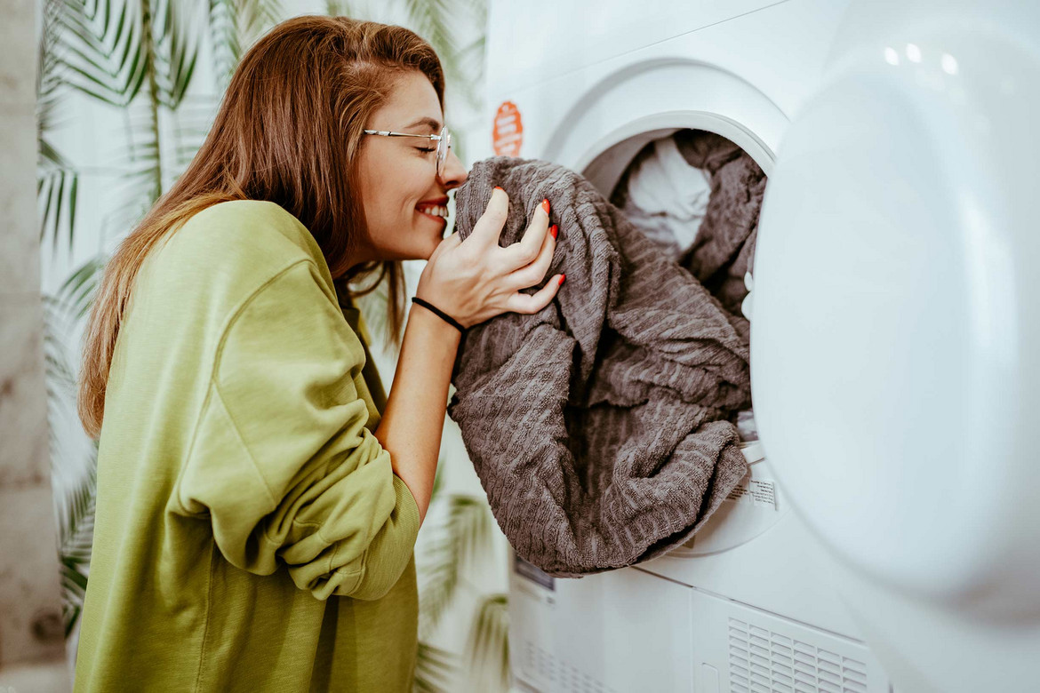 Lächelnde Frau riecht an frisch gewaschener Wäsche