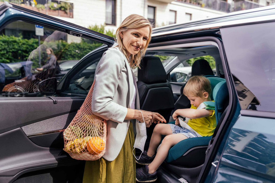 Ein Bild von einer Frau an der Autotür und einem Kind in eine Kindersitz