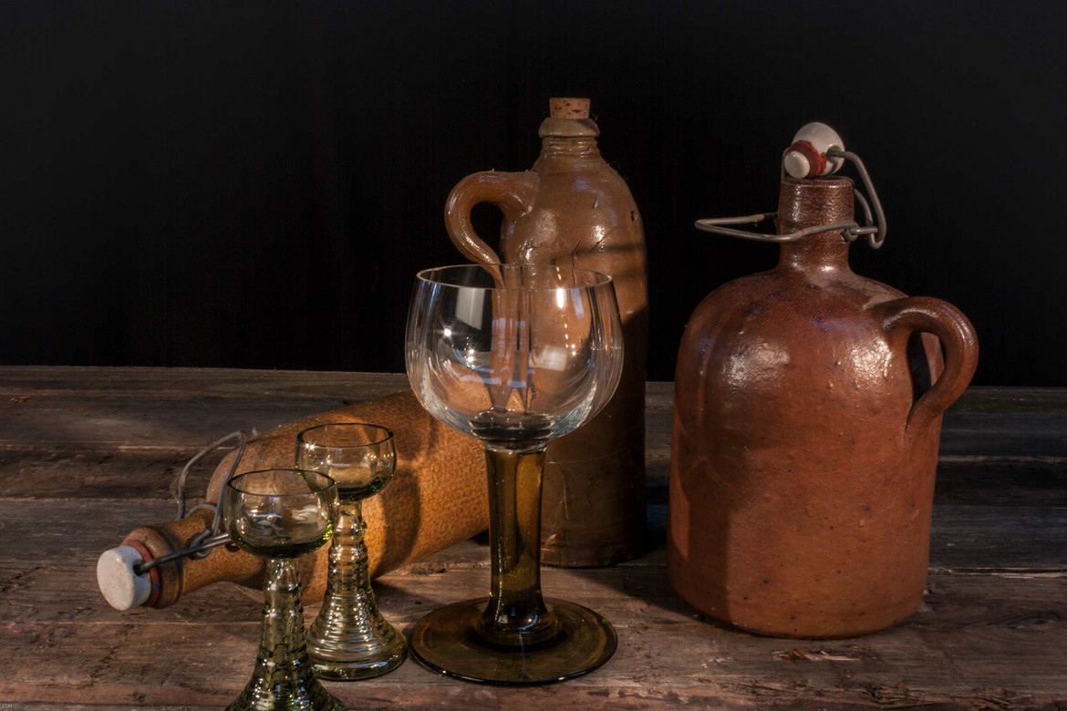 Römergläser und Steingutflaschen auf Holztisch