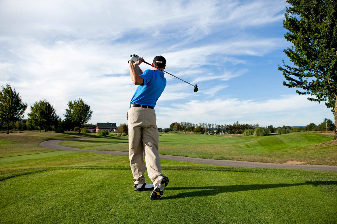 Ein Golfer im richtigen Dresscode auf dem Golfplatz beim Abschlag