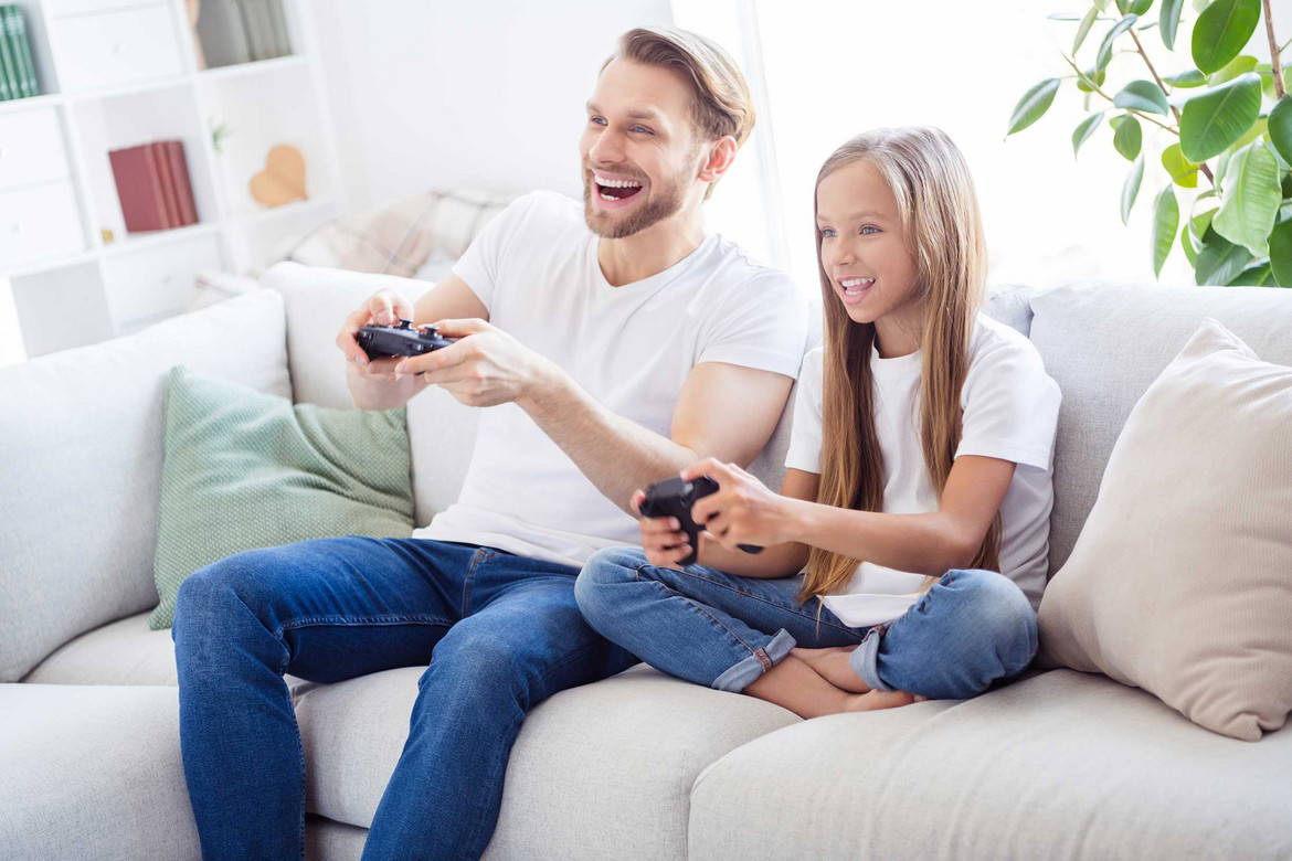 Junger Mann und Mädchen sitzen auf Sofa und spielen mit Nintendo Switch
