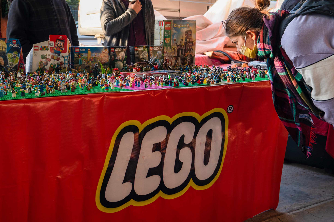 Lego verkaufen: Frau schaut Flohmarkttisch mit Lego an
