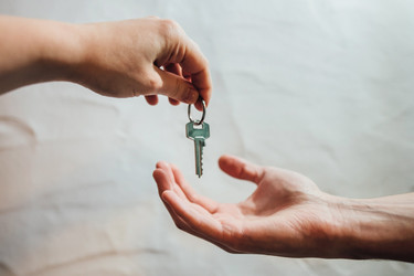 Eine Hand übergibt einen Wohnungsschlüssel an eine andere Hand